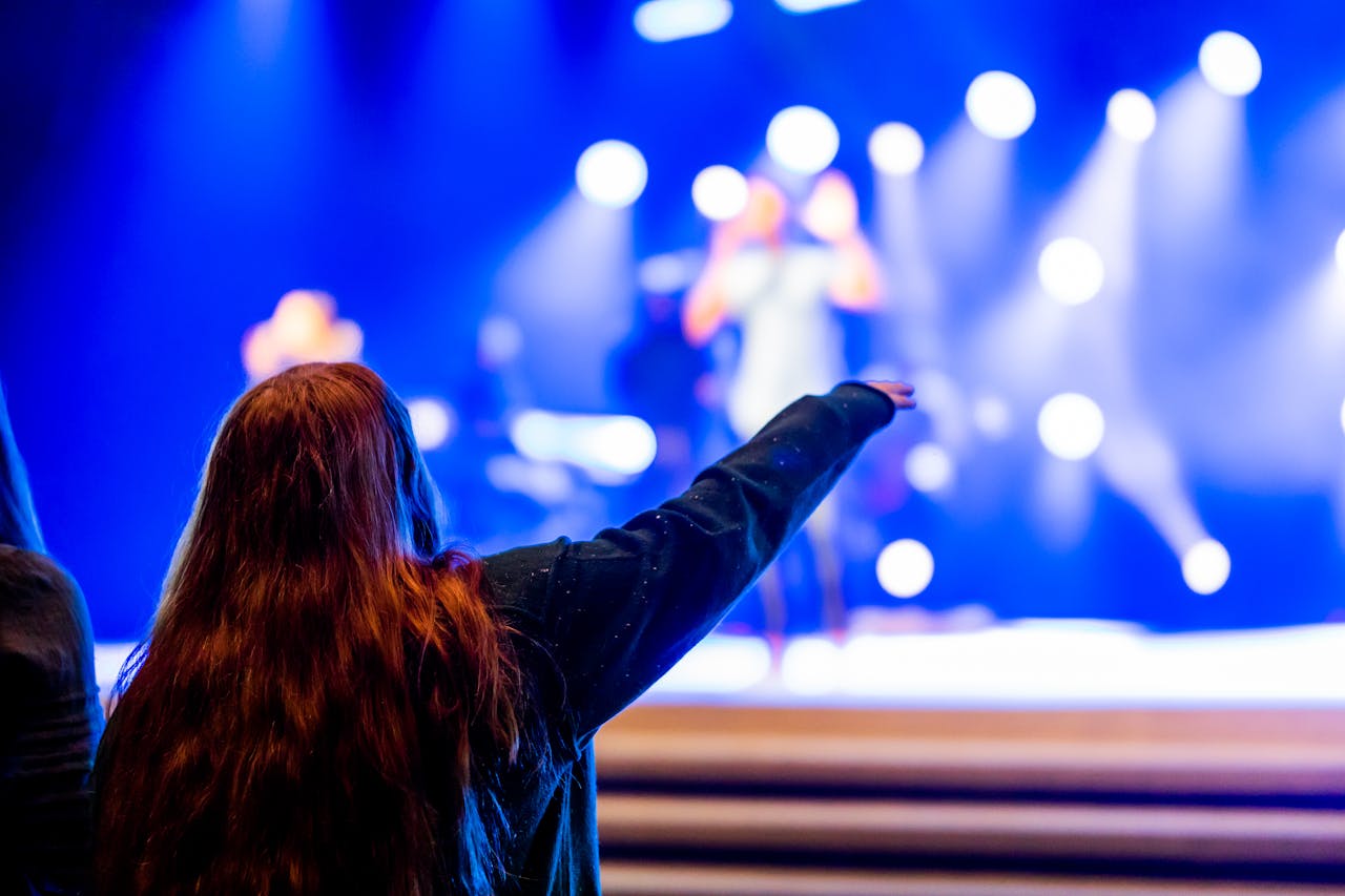 A vibrant concert scene with an engaged audience member enjoying live music on stage.