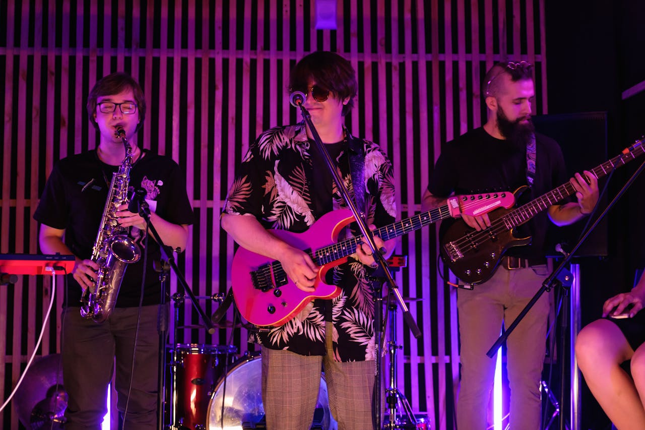 Energetic live performance by a band with electric guitar, saxophone, and bass.
